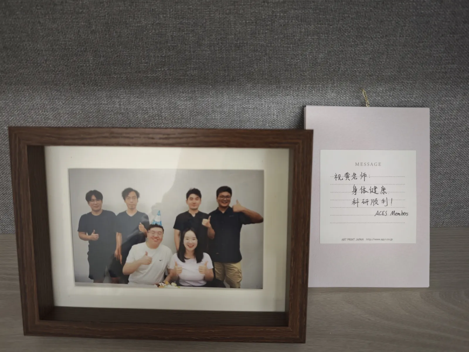 A framed group photograph and handwritten message from ACES Lab members